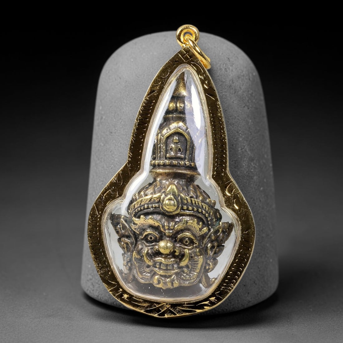 Thai Double-Sided Guardian Head Amulet - Gold Cased Votive Pendant, 8YY: Cast metal devotional piece featuring two distinct sculpted faces visible through clear casing; one side displays ornate guardian demon head with layered crown detailing, the reverse bears intricate s