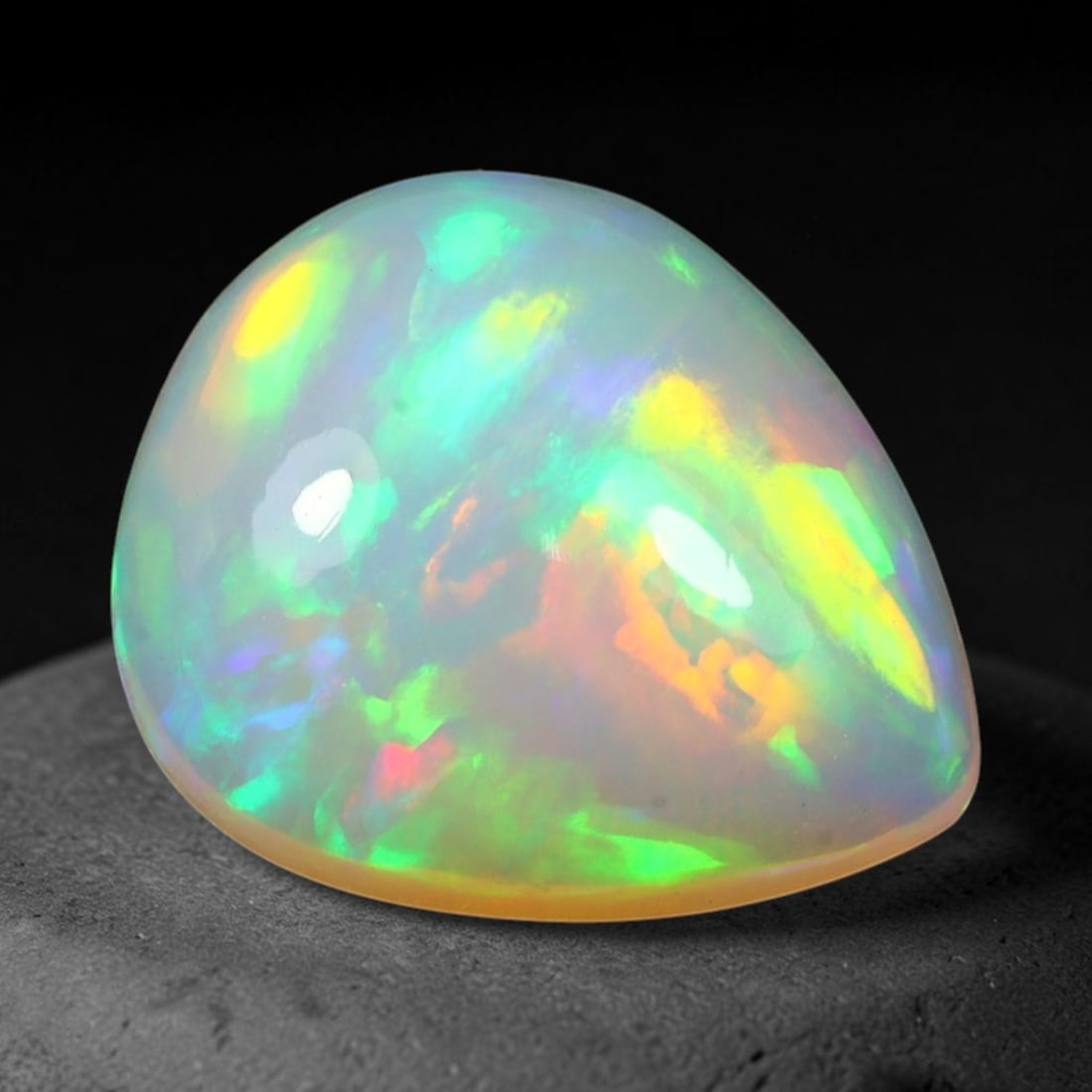 6.40ct Natural Ethiopian Welo Solid Opal Freeform Cabochon, 4TG: This natural solid opal cabochon originates from Ethiopia Welo. The translucent pale base displays lively play-of-color with bright green, golden yellow and warm orange iridescent flashes across the p