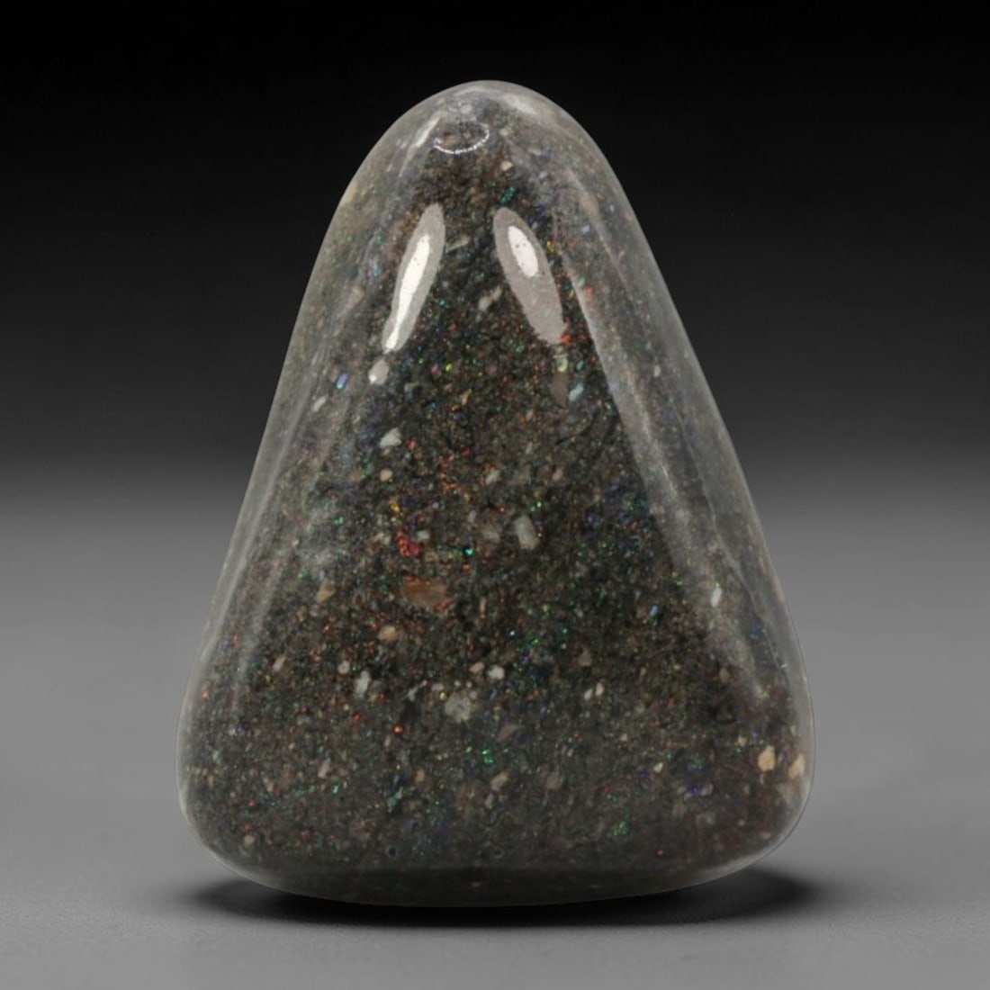 12.26 Carats Australian Matrix Opal Triangular Cabochon - Natural Stone, 71XB: This singular triangular cabochon matrix opal, measuring 19.8 x 15.2 x 7.1 mm, showcases a dramatic dark host matrix studded with vibrant, multicolored opal flecks. The polished surface reveals a dyna
