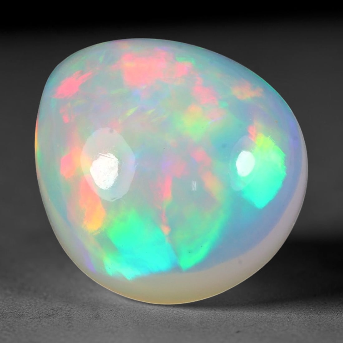 10.39ct Natural Ethiopian Welo Solid Opal Oval Cabochon, 6TG: This natural solid opal cabochon originates from Ethiopia Welo. The translucent pale base features striking multi-hued play-of-color with vivid pink, bright green, golden yellow and soft blue iridesce