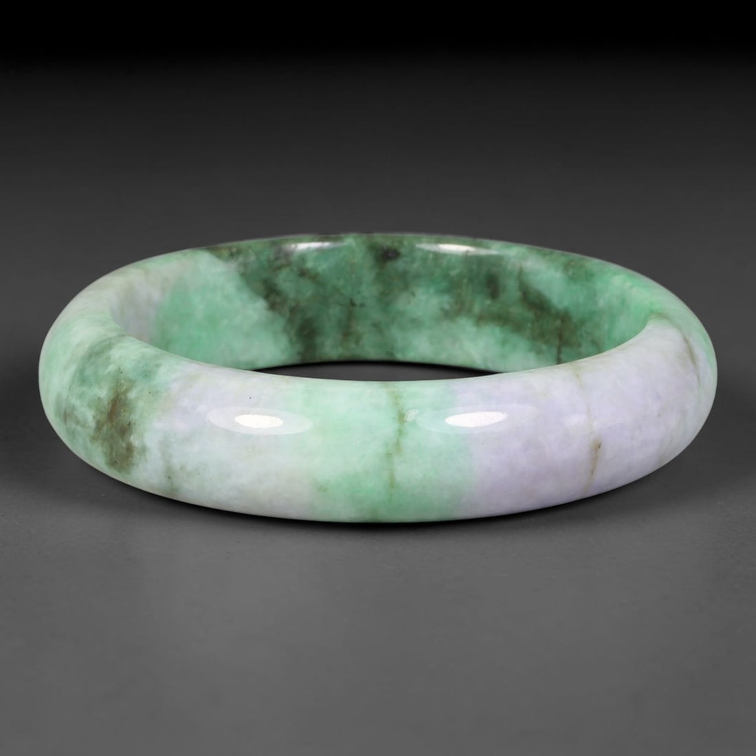 Natural Burmese Type A Jadeite Jade Bangle Bracelet, 10TD: Crafted from natural Burmese type-A jadeite, this broad substantial bangle presents a striking combination of soft lavender-white, bright apple-green and deep forest-green tonal zones across the wide 