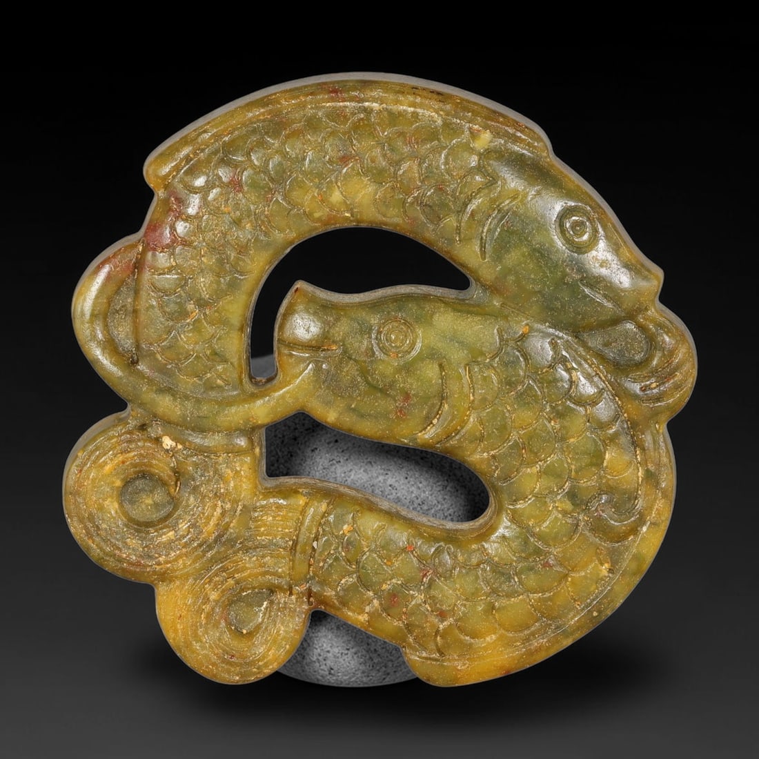 A Chinese Open-Work Carved Jade Stone Twin-Fish Pendant, 69WT: Expertly carved open-work jade pendant displaying interlocking twin-fish motif. Fine incised scale detailing covers each fish body, paired with scrolling decorative elements. Mottled yellow-green jade