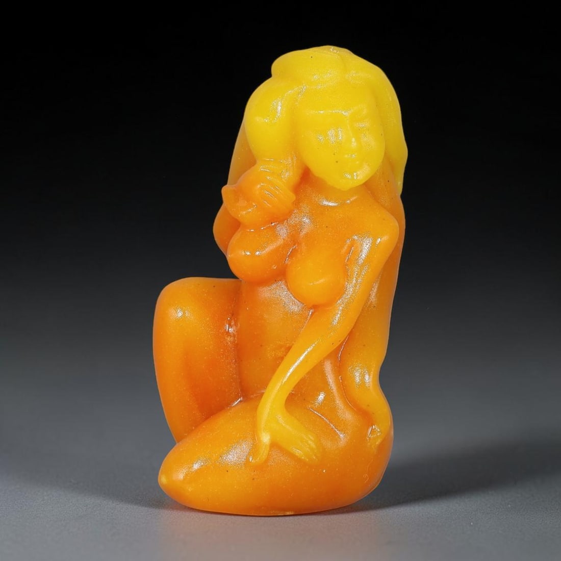 A Chinese Carved Golden-Orange Stone Seated Female Figure Ornament, 28ZQ: Solid carved stone figurine depicting a stylized seated female form with flowing hair and soft rounded body contours. Smooth polished finish with natural colour gradient transitioning from bright yell