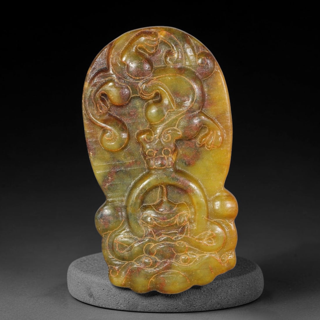 A Chinese Relief-Carved Mottled Yellow-Green Jade Stone Mythical Creature Pendant, 90YF: Irregular shaped jade pendant with flowing organic outline. The obverse features elaborate relief and incised carving of a mythical creature intertwined with scrolling decorative patterns. The stone d
