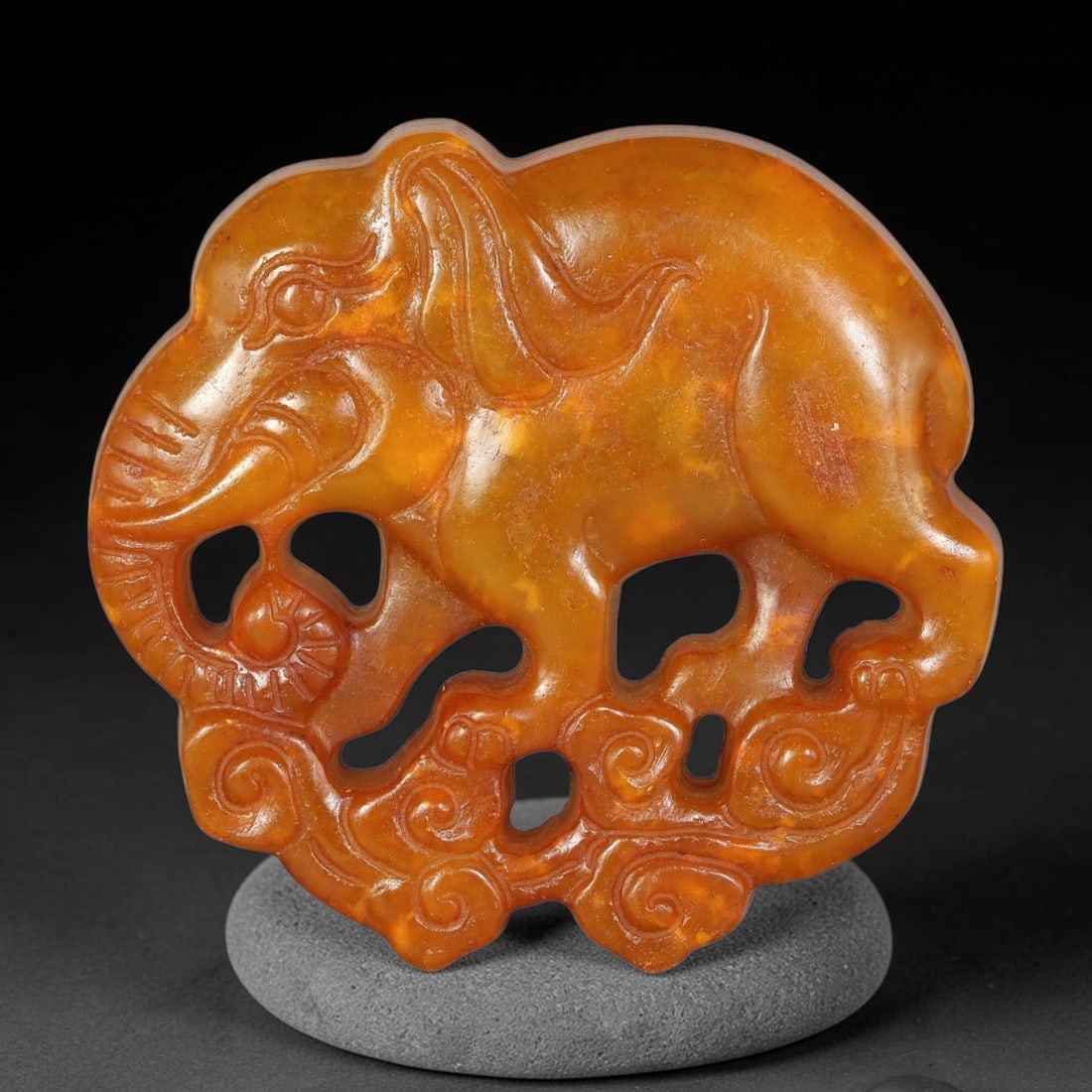 A Chinese Open-Work Carved Brown Jade Stone Elephant Pendant, 70WT: Expertly crafted pierced open-work Jade Stone pendant in warm golden-brown hue. Front face features finely relief-carved elephant figure standing atop swirling cloud motifs, with multiple hollow cut-o