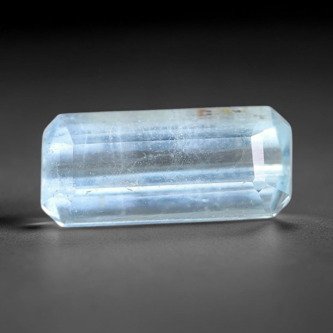 1.76ct Natural Light Blue Aquamarine Emerald Cut Loose Gemstone, 11YW: This faceted aquamarine specimen displays pale light blue colouration with fine linear internal inclusions and minor mineral traces within the transparent beryl crystal. The emerald cut features polis