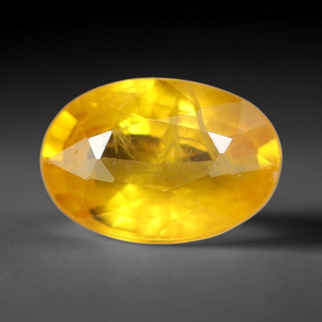 0.94 Carats Natural Yellow Sapphire Oval Faceted Loose Gemstone, 41TT: This natural yellow sapphire features a classic oval brilliant faceted cut, holding consistent warm golden-yellow color throughout the corundum crystal. Fine microscopic mineral specks and faint natur