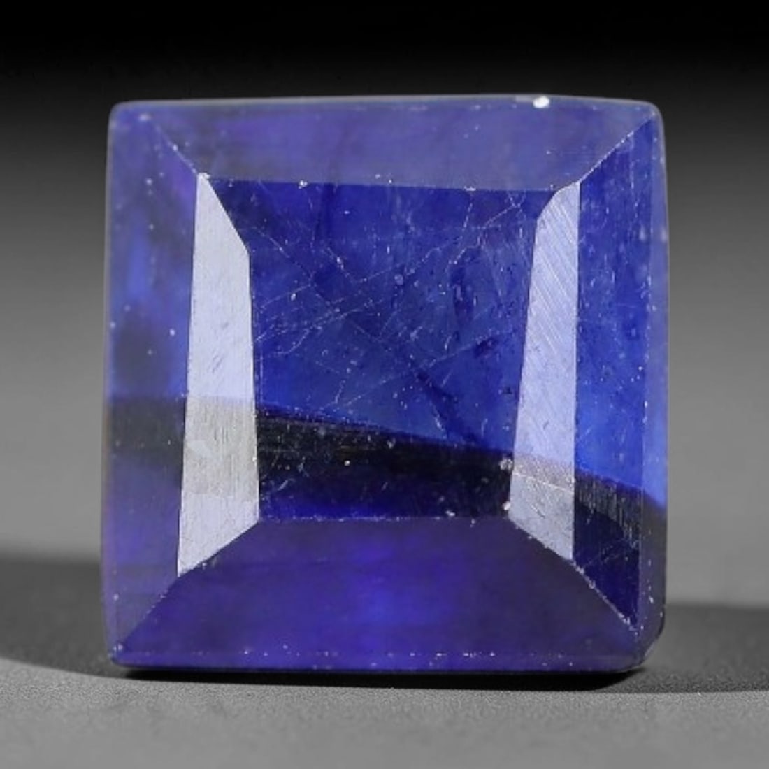 1.64 Carats Royal Blue Sapphire Square Emerald Cut Loose Gemstone, 5YW: This neat square emerald cut sapphire showcases deep, saturated royal blue color, enhanced by clean reflective step facets. Natural internal fine fissures and scattered tiny mineral specks can be obse