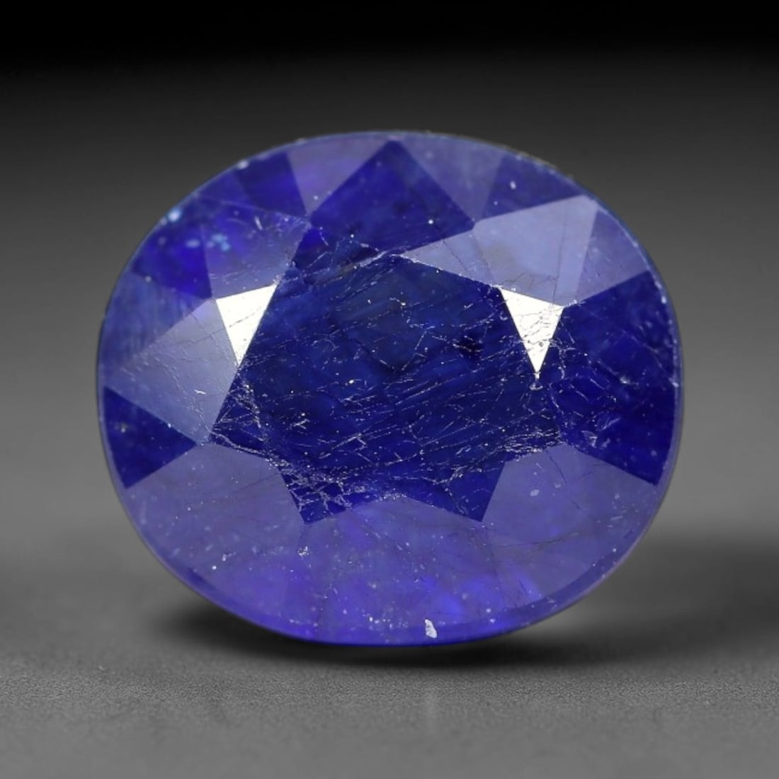 7.43 Carats Royal Blue Sapphire Oval Cut Loose Gemstone, 90TM: This neat oval cut sapphire showcases deep, saturated royal blue color, enhanced by clean reflective step facets. Natural internal fine fissures and scattered tiny mineral specks can be observed withi