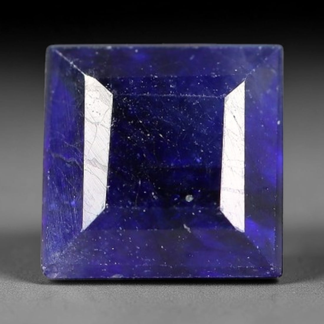 1.61 Carats Royal Blue Sapphire Square Emerald Cut Loose Gemstone, 4YW: This neat square emerald cut sapphire showcases deep, saturated royal blue color, enhanced by clean reflective step facets. Natural internal fine fissures and scattered tiny mineral specks can be obse