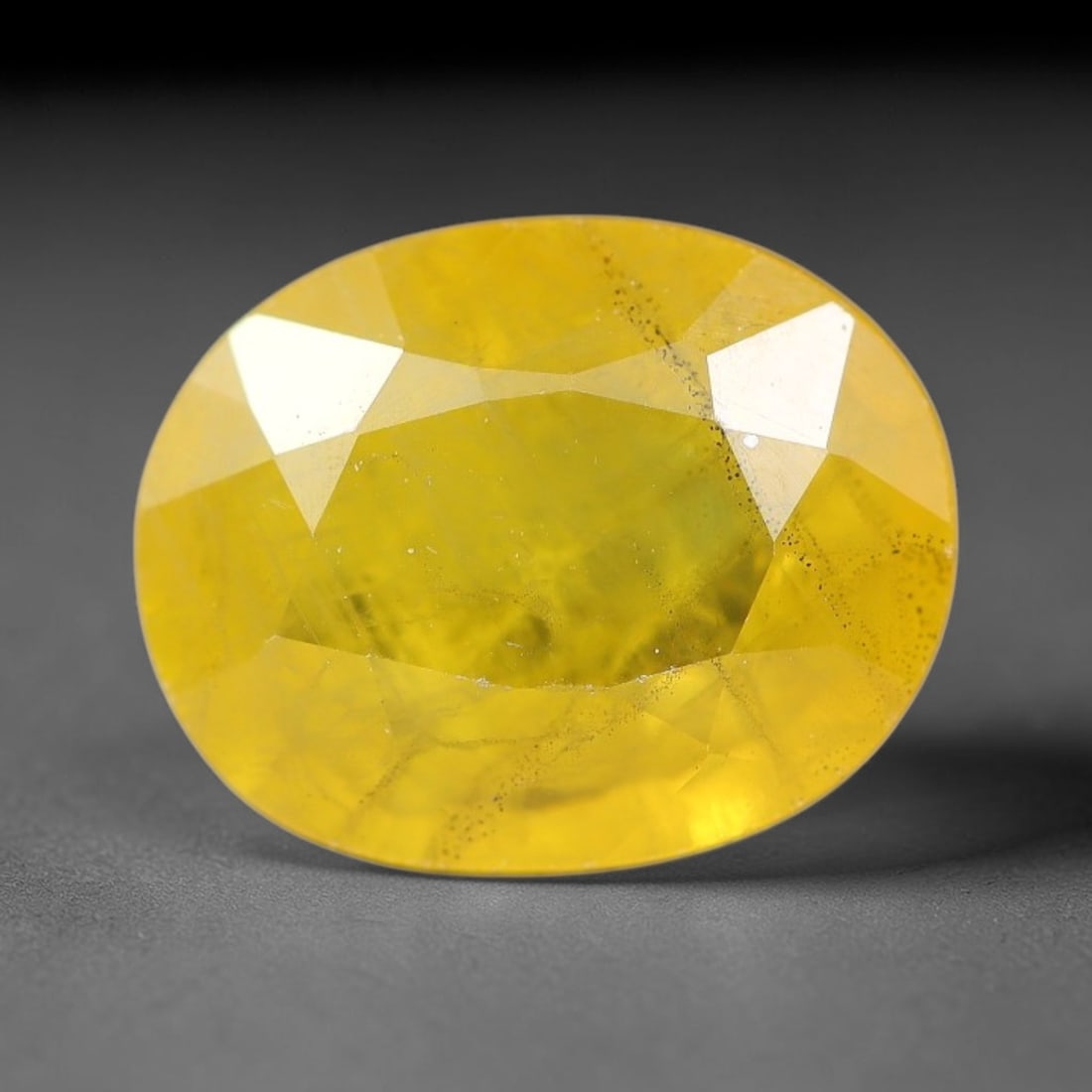 2.35 Carats Natural Yellow Sapphire Oval Faceted Loose Gemstone, 52YW: This natural yellow sapphire features a classic oval brilliant faceted cut, holding consistent warm golden-yellow color throughout the corundum crystal. Fine microscopic mineral specks and faint natur
