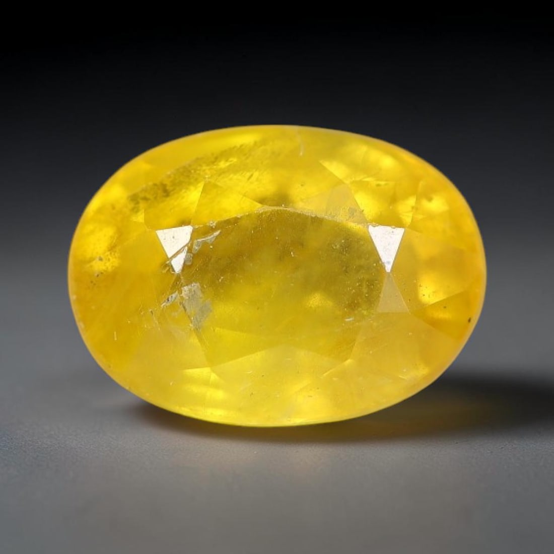 1.23 Carats Natural Yellow Sapphire Oval Faceted Loose Gemstone, 55TT: This natural yellow sapphire features a classic oval brilliant faceted cut, holding consistent warm golden-yellow color throughout the corundum crystal. Fine microscopic mineral specks and faint natur