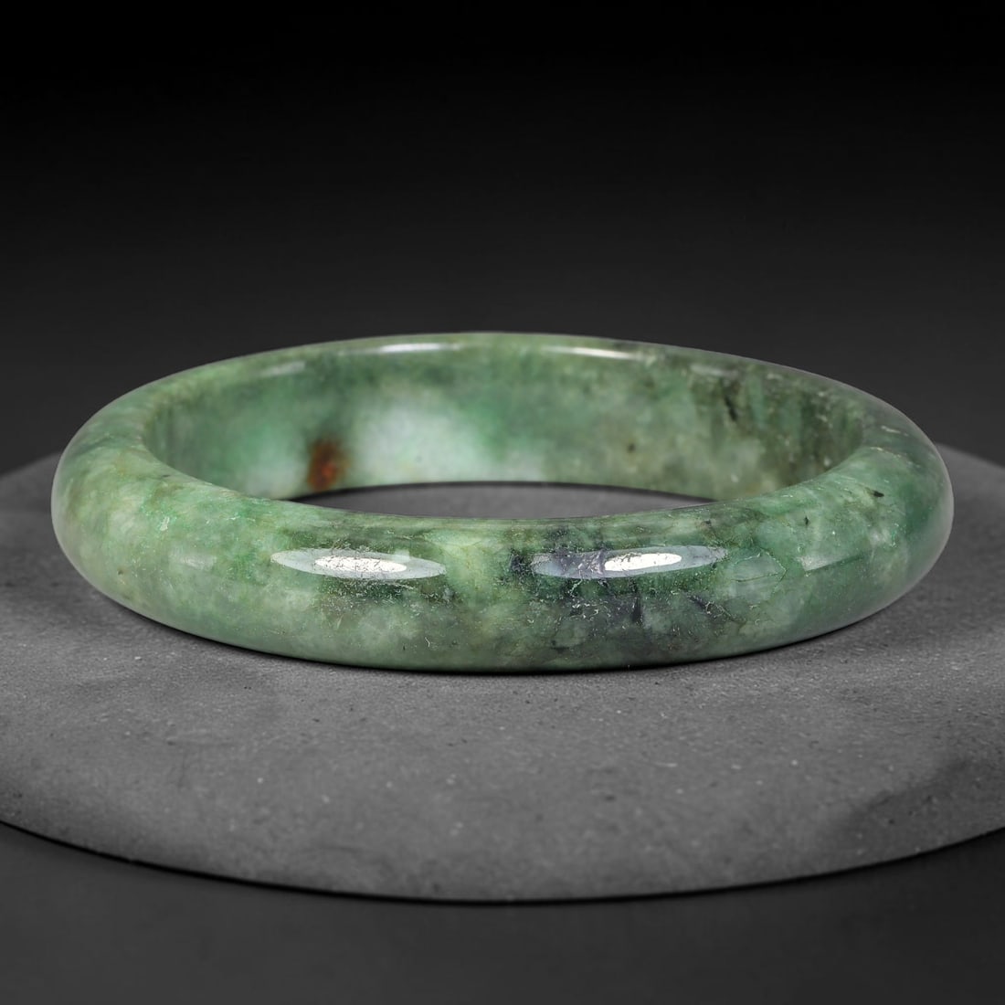 Natural Burmese Type A Moss Floating Green Jadeite Jade Bangle Bracelet, 60TD: Polished jadeite bangle featuring deep mossy green tones blended with natural dark mineral veining and subtle russet speckles. Inner dimension 62.0x13.8mm, smooth rounded band with rich glossy finish.