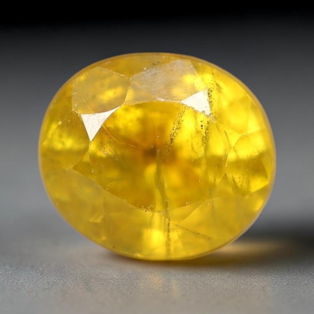 0.89 Carats Natural Yellow Sapphire Oval Faceted Loose Gemstone, 62TT: This natural yellow sapphire features a classic oval brilliant faceted cut, holding consistent warm golden-yellow color throughout the corundum crystal. Fine microscopic mineral specks and faint natur