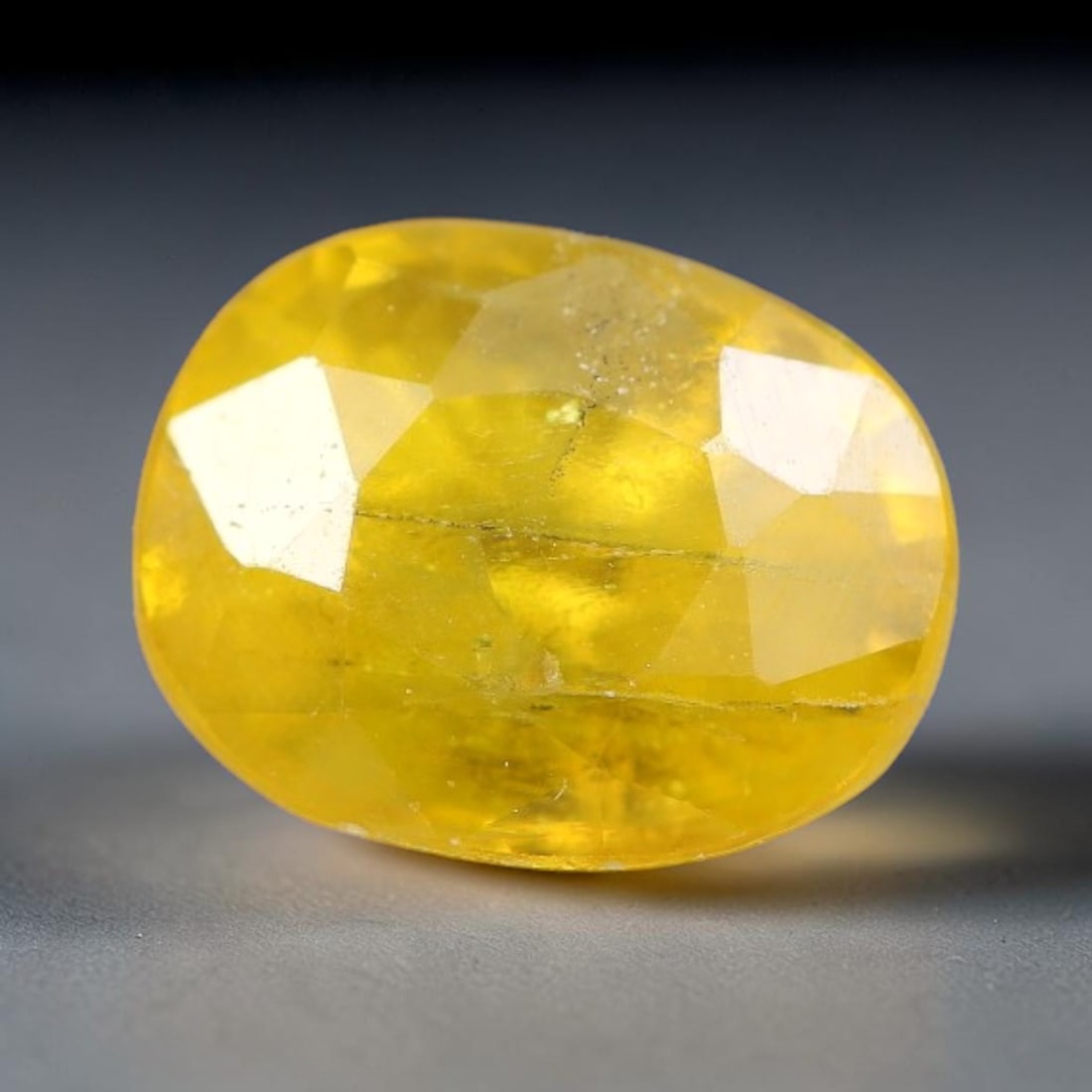 1.40 Carats Natural Yellow Sapphire Oval Faceted Loose Gemstone, 64TT: This natural yellow sapphire features a classic oval brilliant faceted cut, holding consistent warm golden-yellow color throughout the corundum crystal. Fine microscopic mineral specks and faint natur