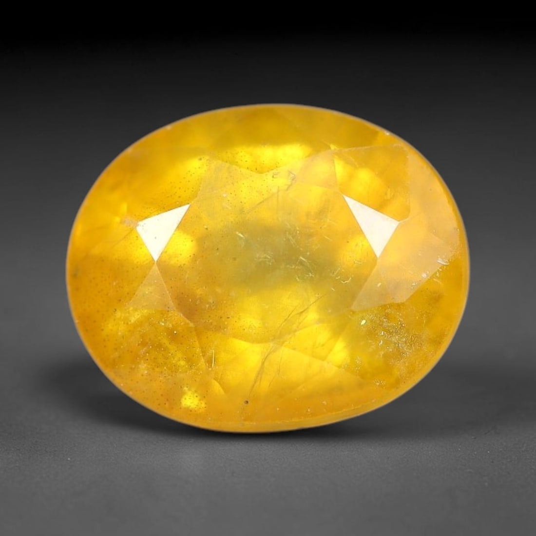 1.82 Carats Natural Yellow Sapphire Oval Faceted Loose Gemstone, 58TT: This natural yellow sapphire features a classic oval brilliant faceted cut, holding consistent warm golden-yellow color throughout the corundum crystal. Fine microscopic mineral specks and faint natur
