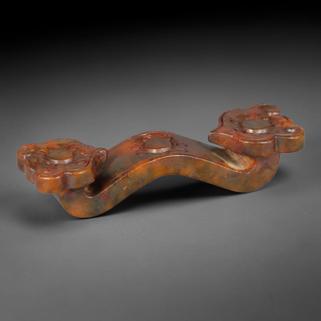 A Chinese Relief-Carved Mottled Russet-Green Jade Stone Ruyi Scepter Ornament, 27ZQ: Miniature carved jade ruyi scepter with characteristic curved silhouette and foliate-form terminals. Both ends and central body are decorated with raised circular-motif relief carvings. The jade displ