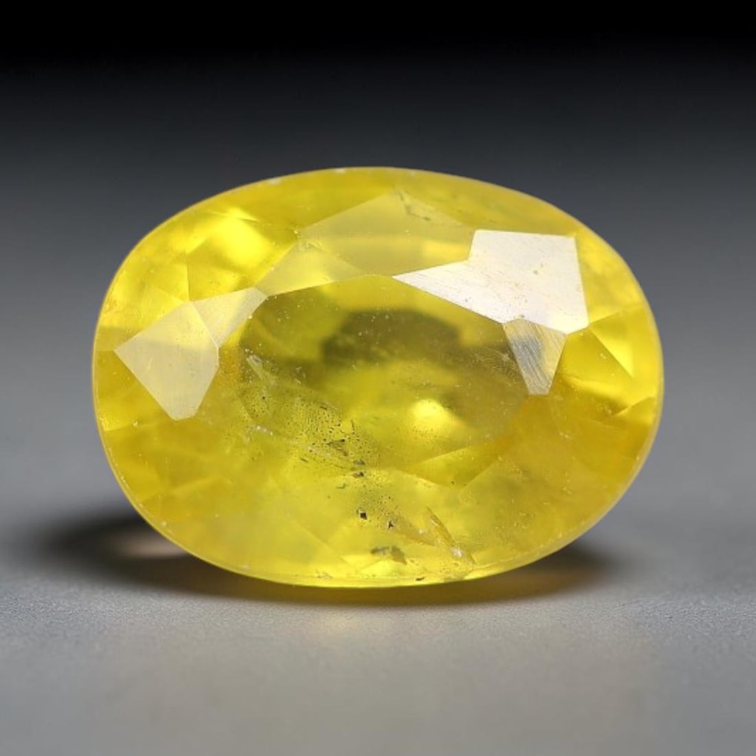 0.97 Carats Natural Yellow Sapphire Oval Faceted Loose Gemstone, 65TT: This natural yellow sapphire features a classic oval brilliant faceted cut, holding consistent warm golden-yellow color throughout the corundum crystal. Fine microscopic mineral specks and faint natur
