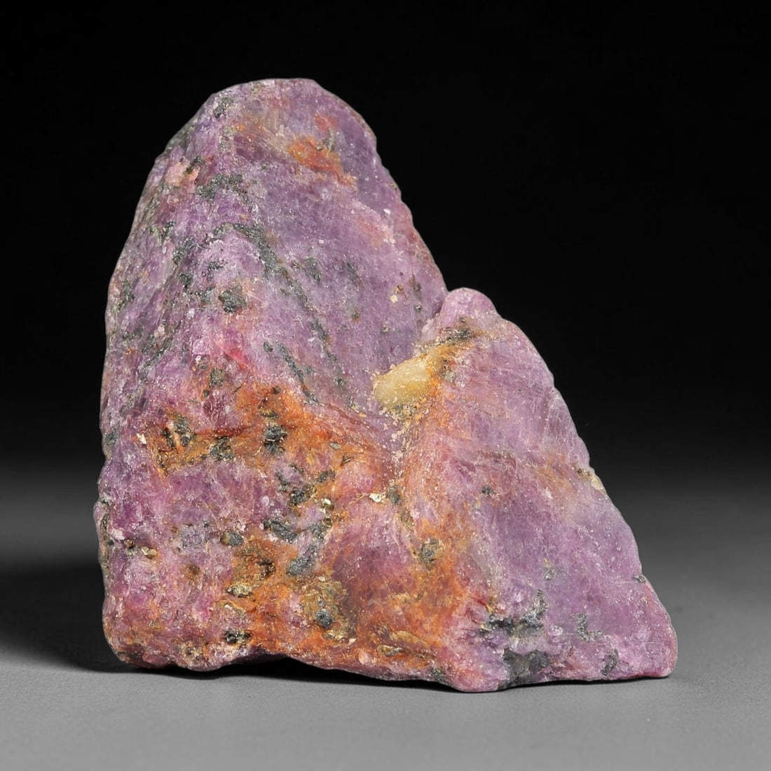 153.41ct Natural Ruby Rough Specimen, 96TV: Natural ruby rough corundum specimen, measuring 43.4x33.1x15.8mm, weight 153.41 carats. Features rich deep purple-red tones with natural mineral veining, dark host mineral inclusions and patches of or