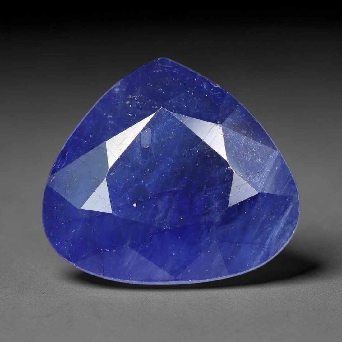 6.89 Carats Royal Blue Sapphire Pear Cut Loose Gemstone, 86TY: This neat pear cut sapphire showcases deep, saturated royal blue color, enhanced by clean reflective step facets. Natural internal fine fissures and scattered tiny mineral specks can be observed withi