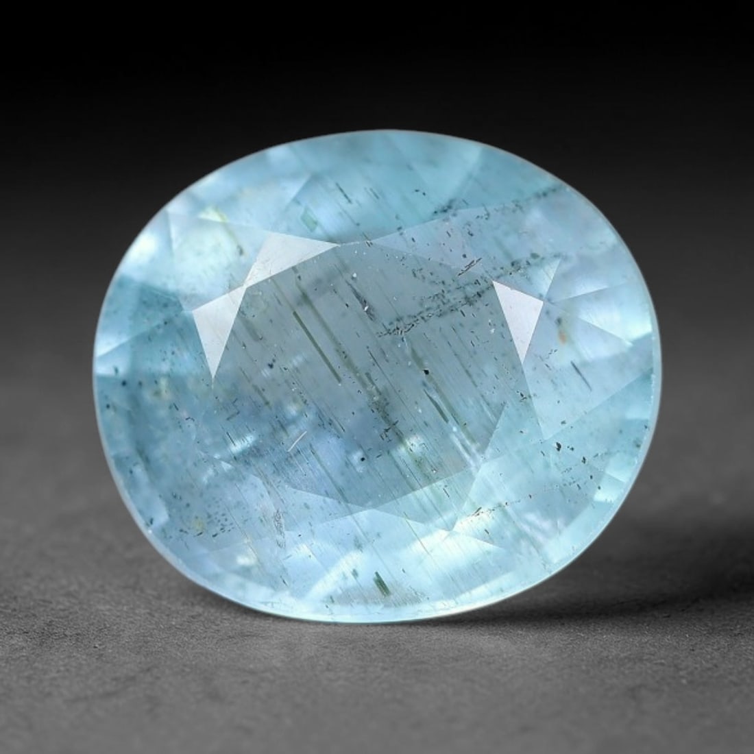 2.98ct Natural Light Blue Aquamarine Oval Cut Loose Gemstone, 6YW: This faceted aquamarine specimen displays a pale light blue colouration with fine needle-like inclusions and minor dark mineral traces visible within the transparent crystal matrix. The oval cut featu