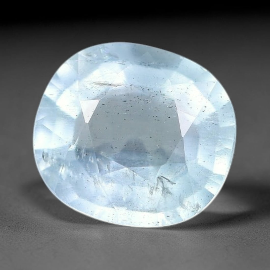 1.38ct Natural Light Blue Aquamarine Oval Cut Loose Gemstone, 12YW: This faceted aquamarine specimen bears a soft pale blue hue, with fine needle-like inclusions and scattered tiny mineral specks visible inside the transparent beryl crystal. The oval cut is finished w