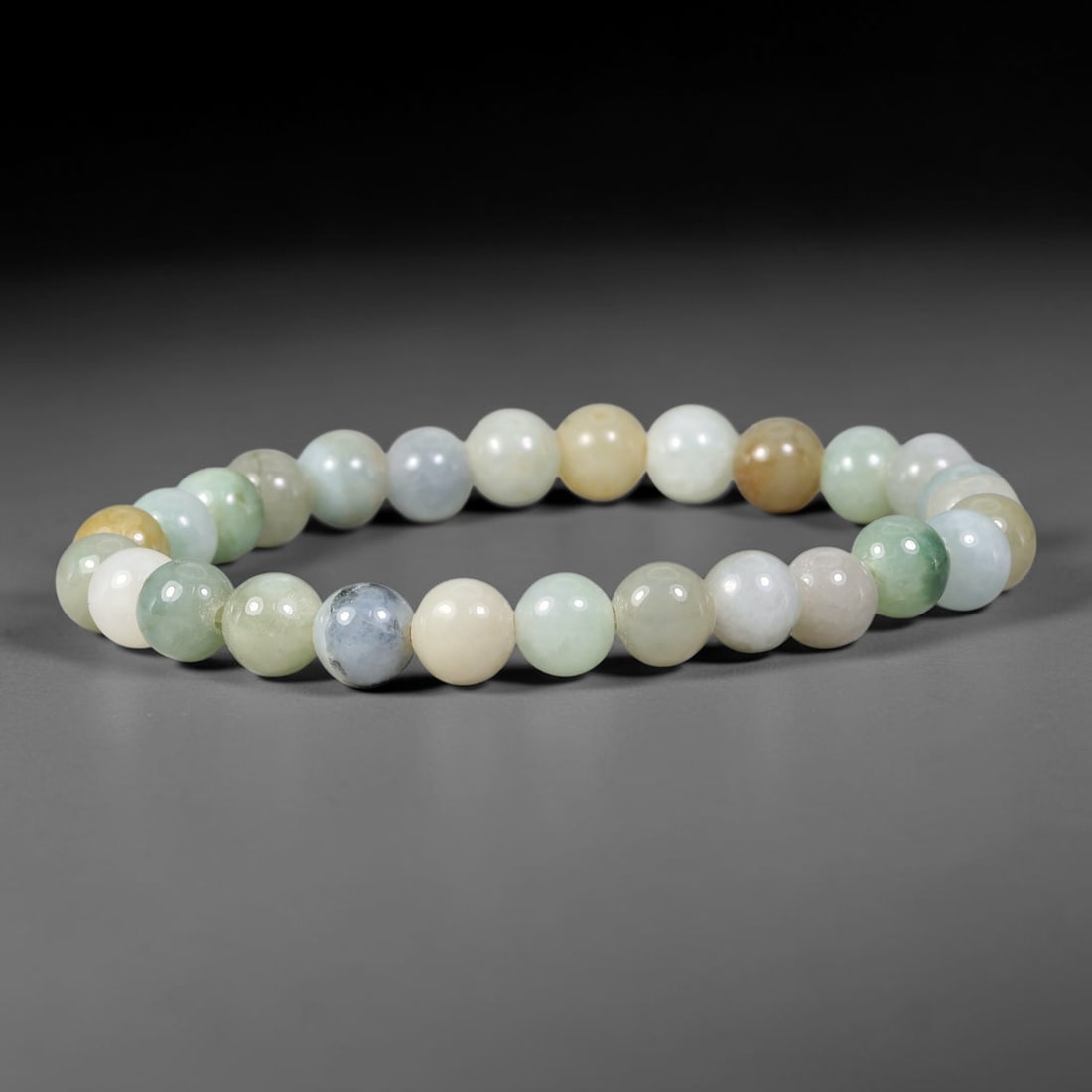 Natural Burmese Type A Multitone Variegated Jadeite Jade Bracelet, 69TK: Hand-strung bracelet crafted from polished round natural Burmese Type A jadeite beads measuring 7.4mm. The beads display a rich mix of milky white, pale celadon, honey yellow and soft greyish-blue mot