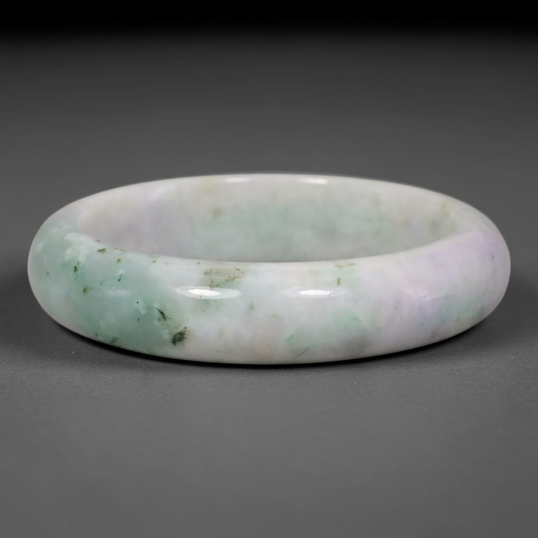 Natural Burmese Type A Lavender Floating Green Speckled Jadeite Jade Bangle Bracelet, 35TD: This solid bangle is crafted from natural Burmese Type A jadeite. The stone displays a pale lavender base blended with soft floating green patches, accented by scattered dark speckled inclusions. The 