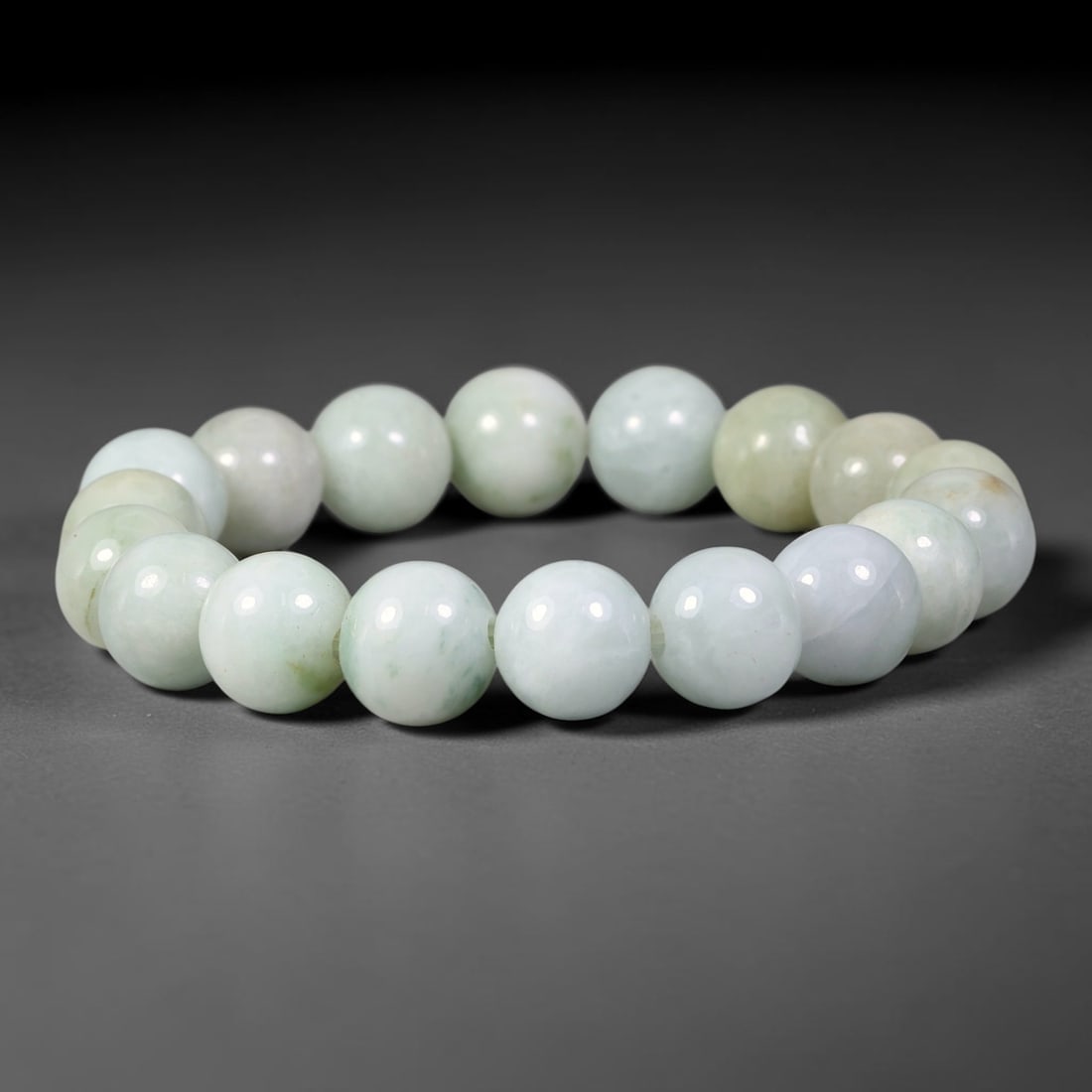 Natural Burmese Type A Pale Celadon Jadeite Jade Bracelet, 68TK: Hand-strung bracelet with polished round natural Burmese Type A jadeite beads measuring 11.0mm. The beads show soft pale celadon blended with milky white, accented by faint subtle green mottling. The 