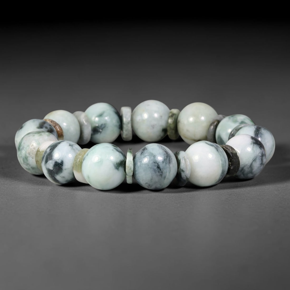 Natural Burmese Type A Ink Floating Jadeite Jade Bracelet, 49TK: Hand-strung bracelet with polished round natural Burmese Type A jadeite beads measuring 13.8mm. The beads feature a milky white base with soft ink-green floating mottling. Thin multi-toned jade disc s