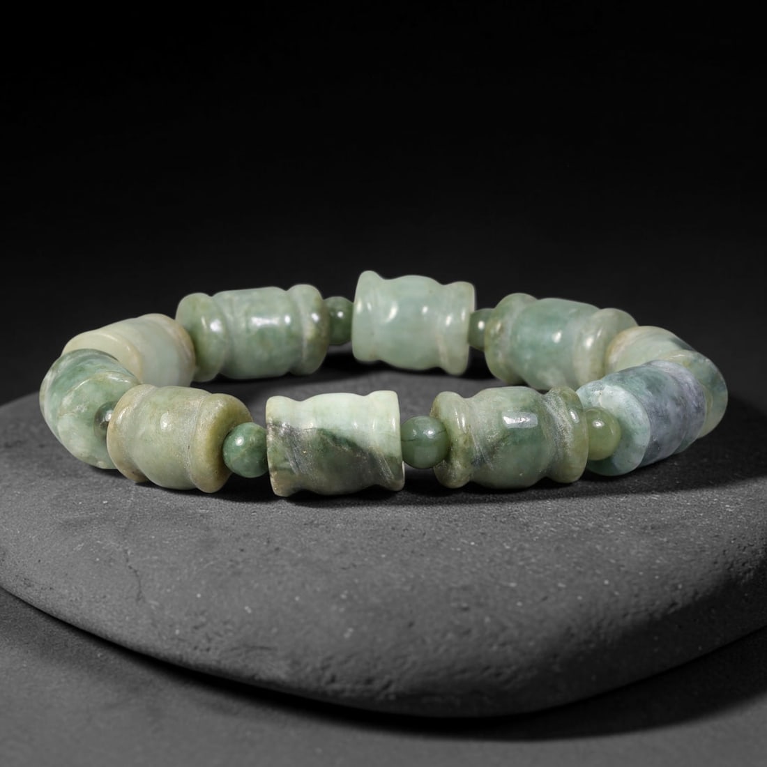 Natural Burmese Type A Carved Barrel Jadeite Jade Bracelet, 57TK: Hand-strung bracelet with carved barrel-shaped natural Burmese Type A jadeite beads measuring 11.7mm. The beads exhibit rich deep green blended with earthy muted tones and natural dark mottling. Small