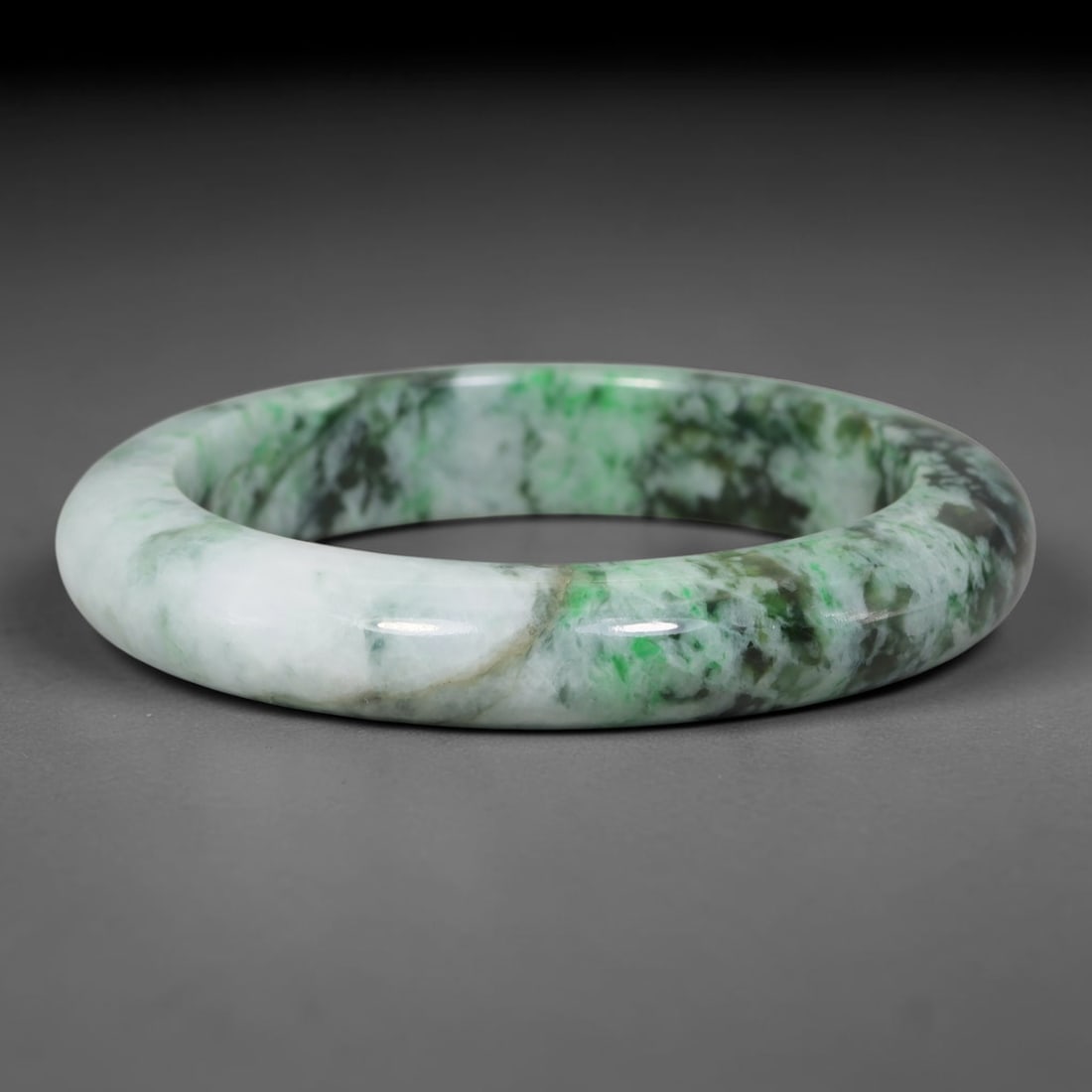 Natural Burmese Type A Variegated Floating Green Jadeite Jade Bangle Bracelet, 24TD: This slender band bangle is crafted from natural Burmese Type A jadeite. The stone features a milky white base overlaid with blended bright and deep green mottled clouding across the surface. The bang