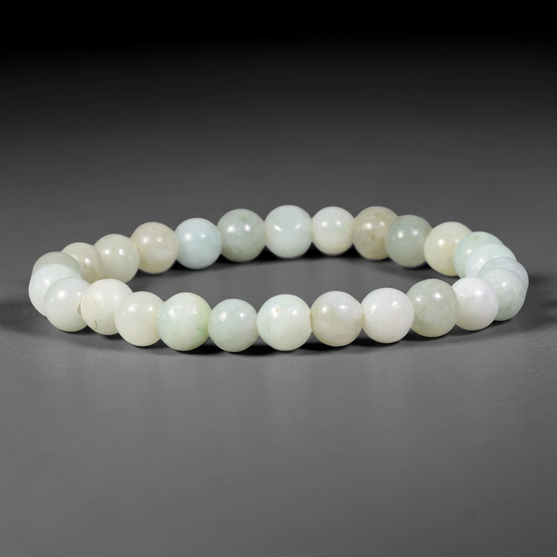 Natural Burmese Type A Pale Celadon Jadeite Jade Bracelet, 62TK: Hand-strung bracelet with polished round natural Burmese Type A jadeite beads measuring 7.8mm. The beads feature milky white base overlaid with soft pale celadon green washes and faint natural beige m