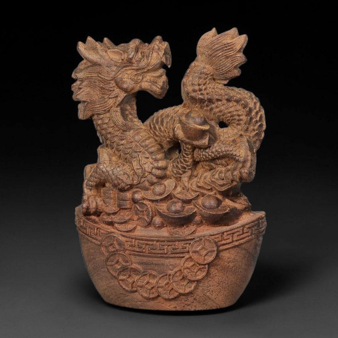A Carved Agarwood Figure of a Dragon Sculpture Figurine, 7SD: Carved from fragrant agarwood (Aquilaria spp.), the work depicts a coiled dragon rising from a treasure vessel, the creature's body detailed with individually rendered scales and flaring mane. The bow