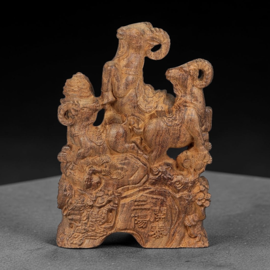A Carved Agarwood Figure of Three Goats Sculpture Figurine, 8SD: Carved from fragrant agarwood (Aquilaria spp.), the work depicts three rams arranged upon an intricately carved rocky base adorned with pine and floral motifs. Openwork carving separates the figures, 