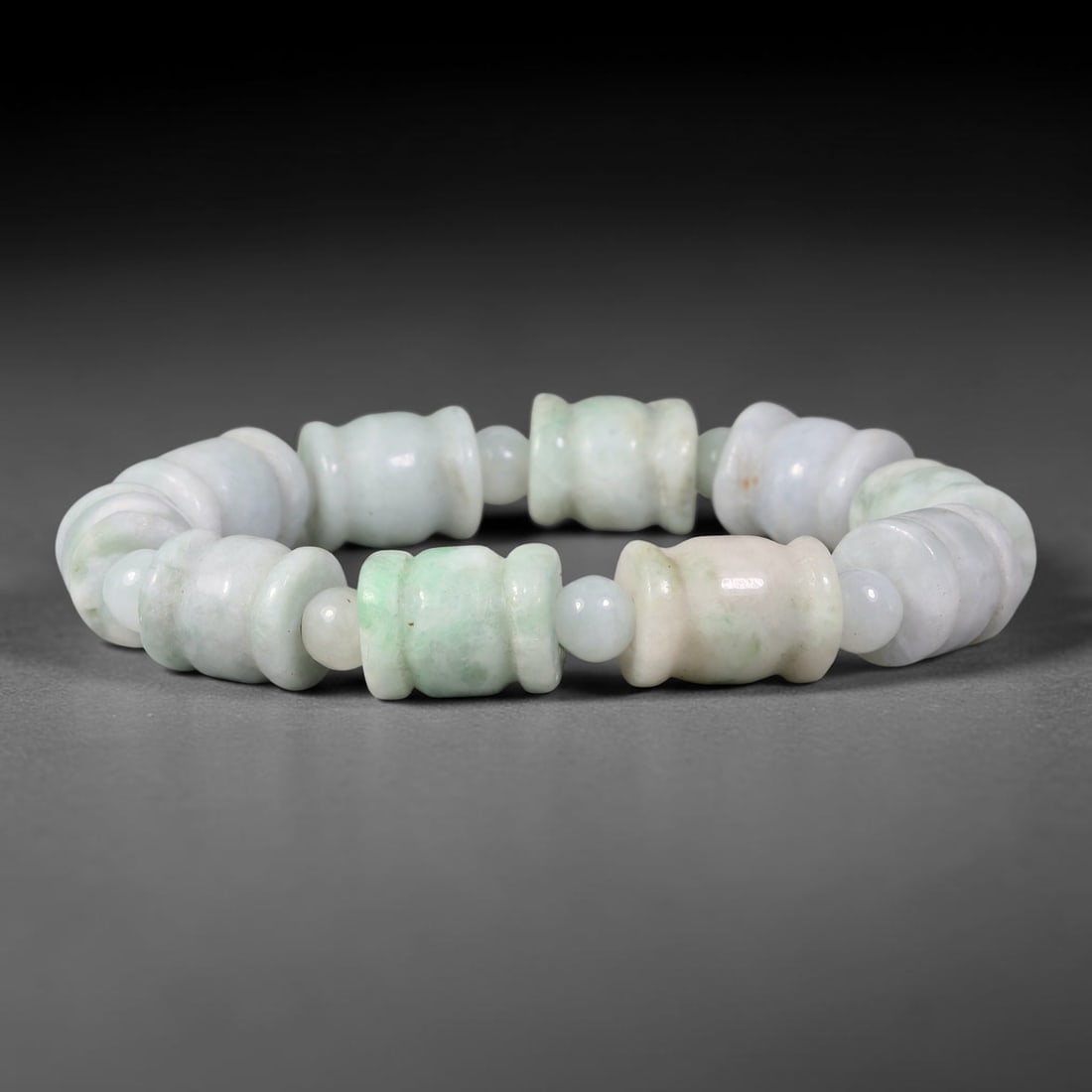 Natural Burmese Type A Carved Barrel Jadeite Jade Bracelet, 54TK: Hand-strung bracelet with carved barrel-shaped natural Burmese Type A jadeite beads measuring 11.7mm. The beads feature a milky white base with soft patches of pale celadon green. Small round jade spa