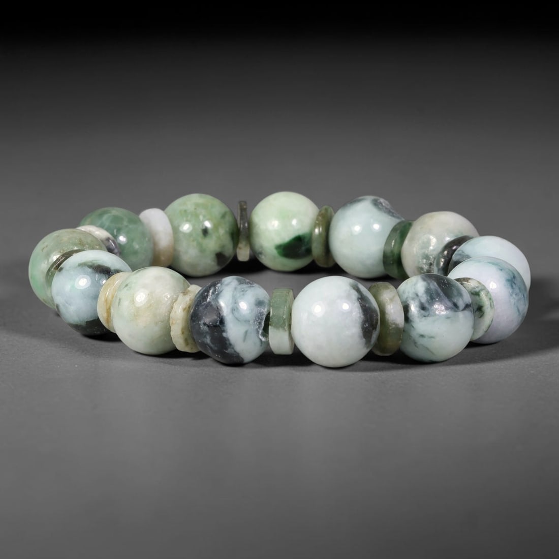 Natural Burmese Type A Multi-Tone Floating Jadeite Jade Bracelet, 46TK: Hand-strung bracelet with polished round natural Burmese Type A jadeite beads measuring 13.8mm. The beads combine milky white base with vibrant green and deep ink-black swirling floating mottling. Thi