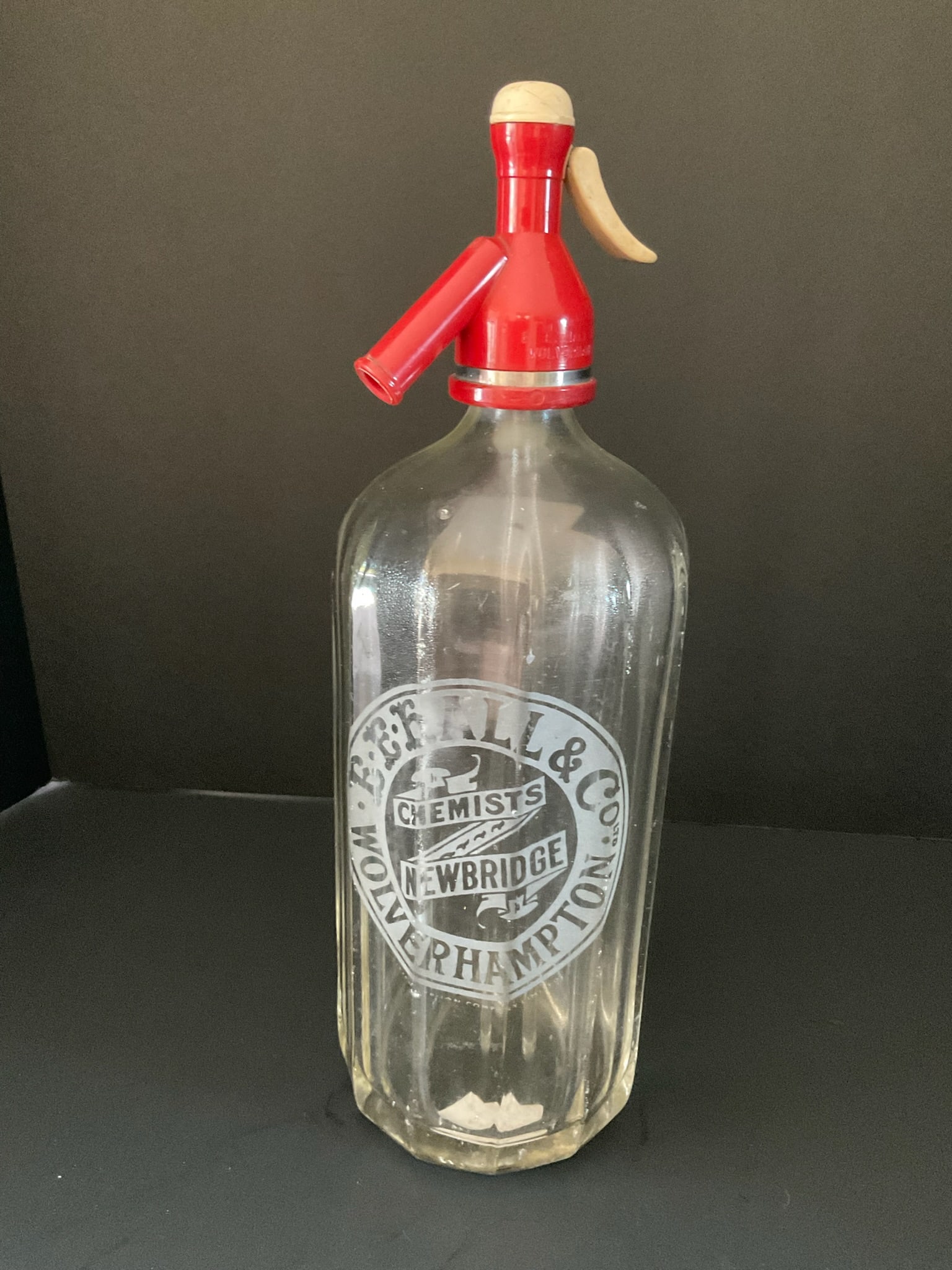 Vintage Glass Seltzer Bottle: A vintage heavy glass seltzer bottle with an unusual red top. The front is etched E E Hall & Co Wolverhampton Chemests Newbridge. It appears to be functioning - the glass rod is still intact. It measu