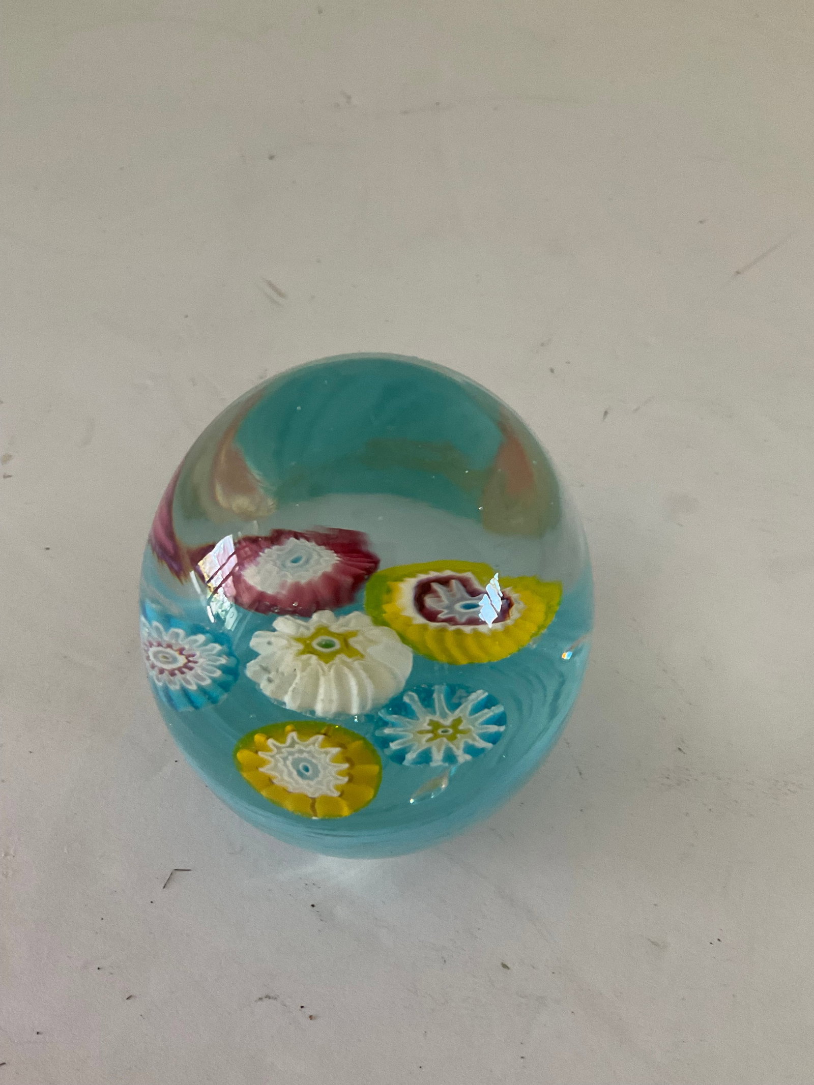 Milliflore Murano Glass Paperweight: A small egg shaped glass Murano paperweight with the original paper sticker to the base. It has a light blue base/vase with six milleflore "flowers". Good condition, measuring approximately 3" in heig
