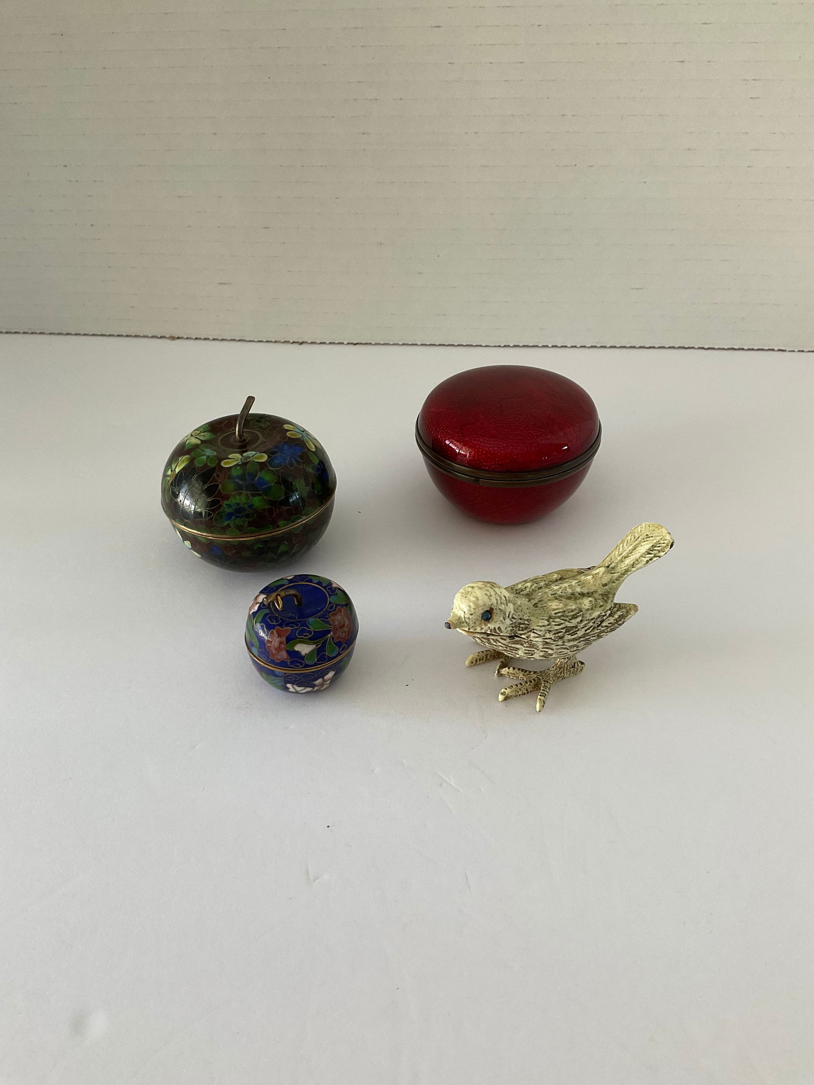 Collection of Three Cloisonné Trinket Boxes and One Bird Pill Box: Included are two vintage apple shaped cloisonné boxes, a deep red enameled box and a metal bird shaped pill box with tweezers. The smallest is 1.5" in diameter
