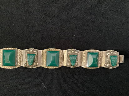 Vintage Hinged Taxco Sterling Bracelet: A stamped Taxco, Mexico sterling silver bracelet with malachite faces and green stone accents. The faces all have earrings except one. It is 7" in length and 1" high. Weight including stones is