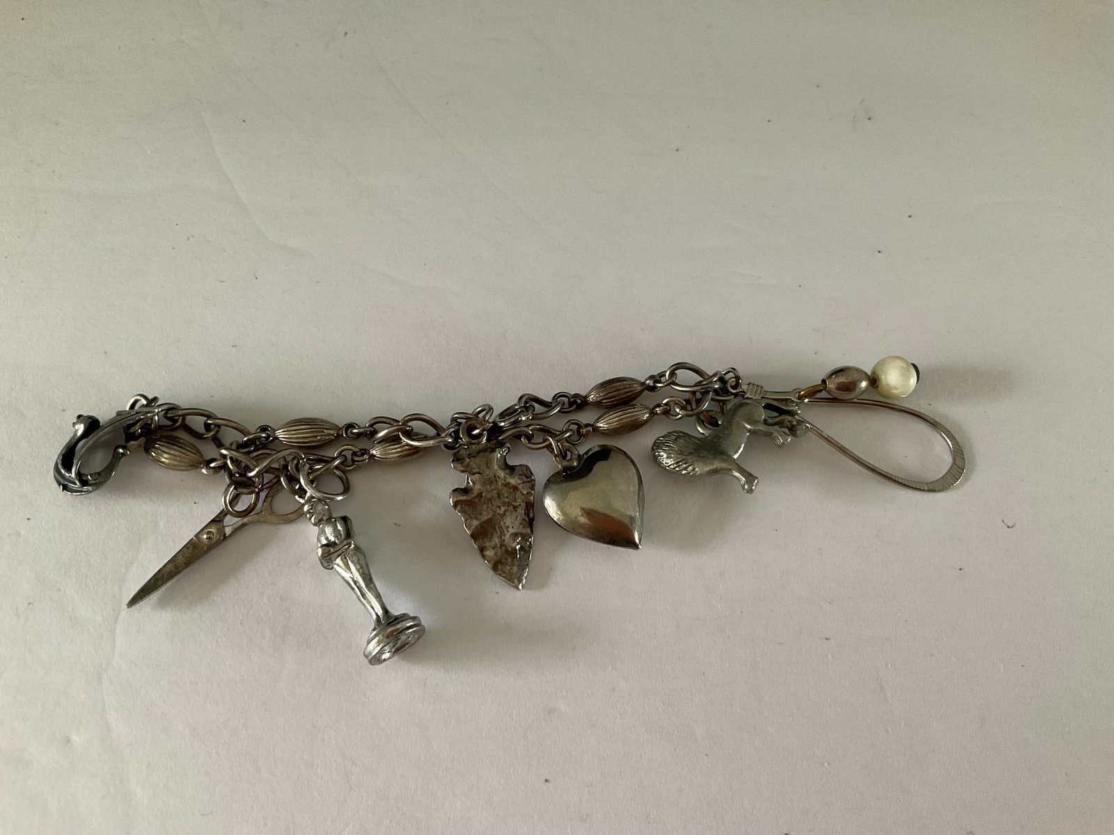 Vintage Silver Charm Bracelet: A vintage Sterling (?) bracelet with seven charms. This does not react with magnet but is not stamped. It measures 6.5"
