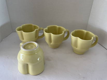 Set of Four Mid Century Clover Shaped Pottery Mugs: A set of four creamy yellow pottery mugs in the shape of clovers. The mugs each have RJB imprinted to the base. Very good condition. Each is 4" high x 5" at the handle