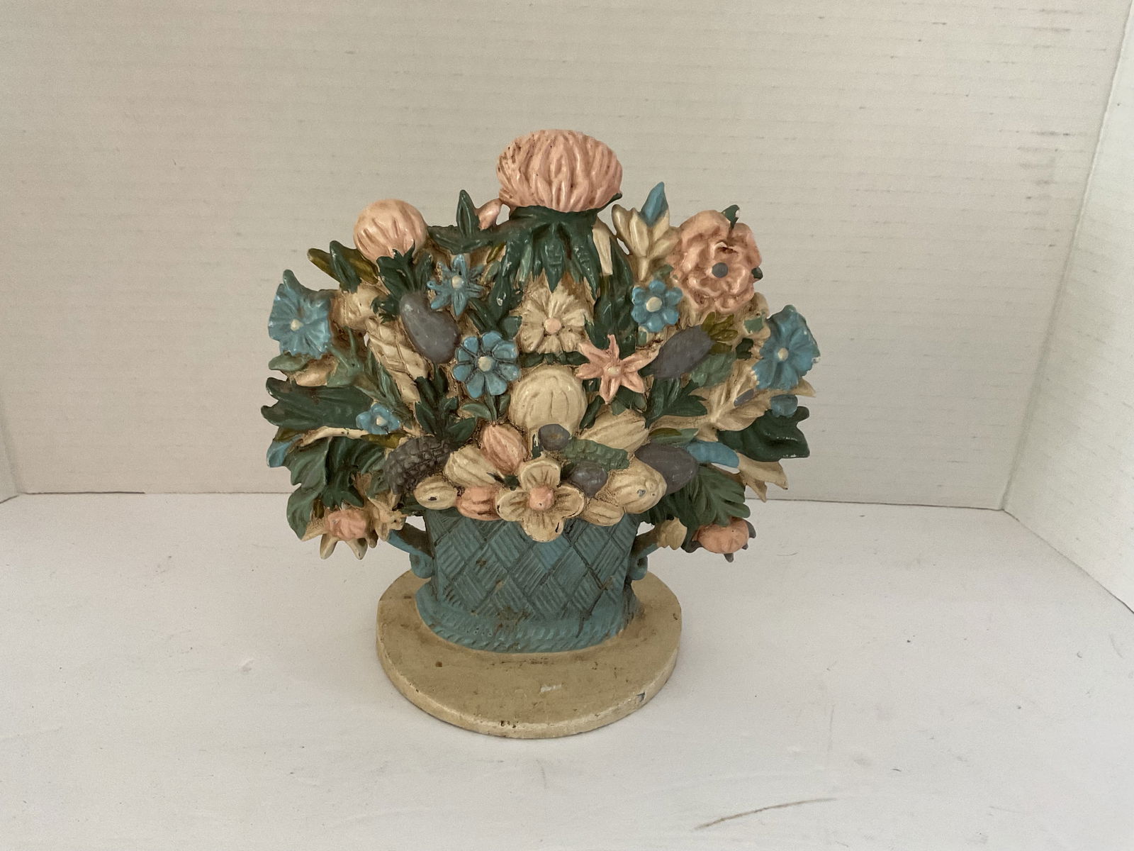Antique Cast Iron Doorstop Basket of Flowers: An antique doorstop in the shape of a basket of flowers. Painted in pastels, it measures 8" x 8" approximately