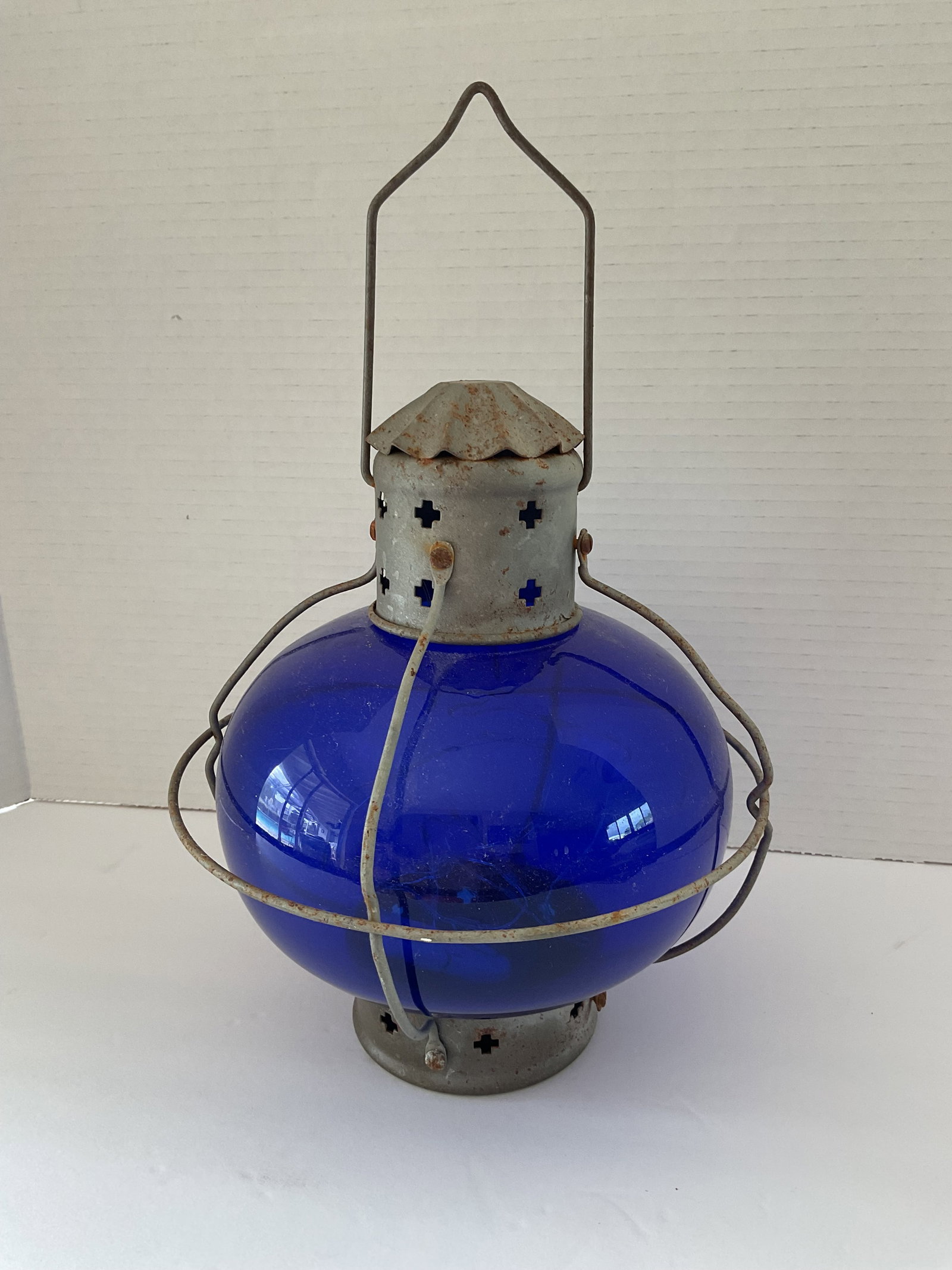 Rustic Cobalt Glass and Tin Lantern: A rustic hanging tin lantern. This piece is fitted with bulbous cobalt hued glass. It measures 13" in height and 9" in diameter