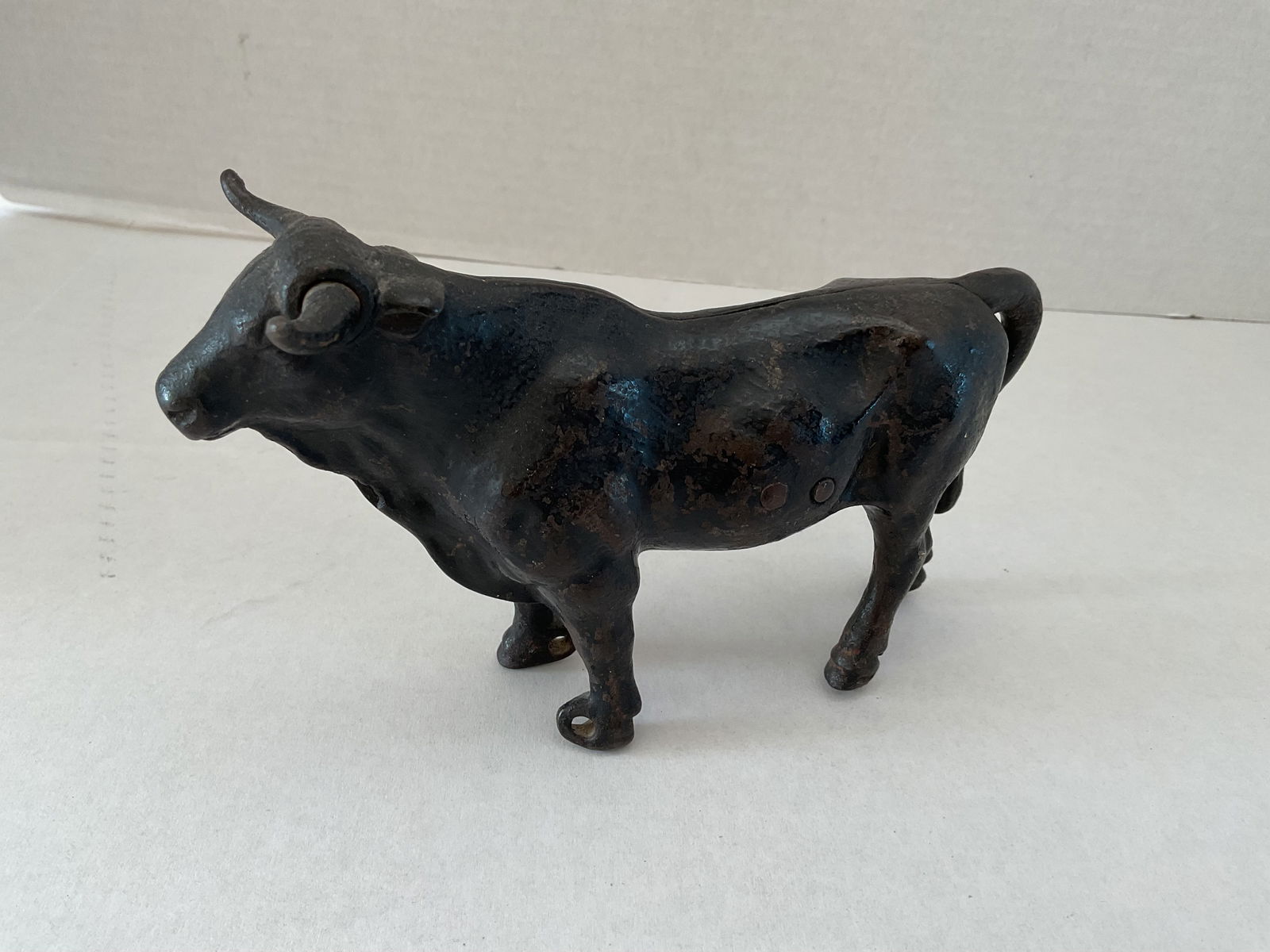 Antique Cast Iron Bull: An antique cast iron bull. This bull is quite detailed and appears like it may have been part of a larger piece. It measures 7"h x 8" in length.