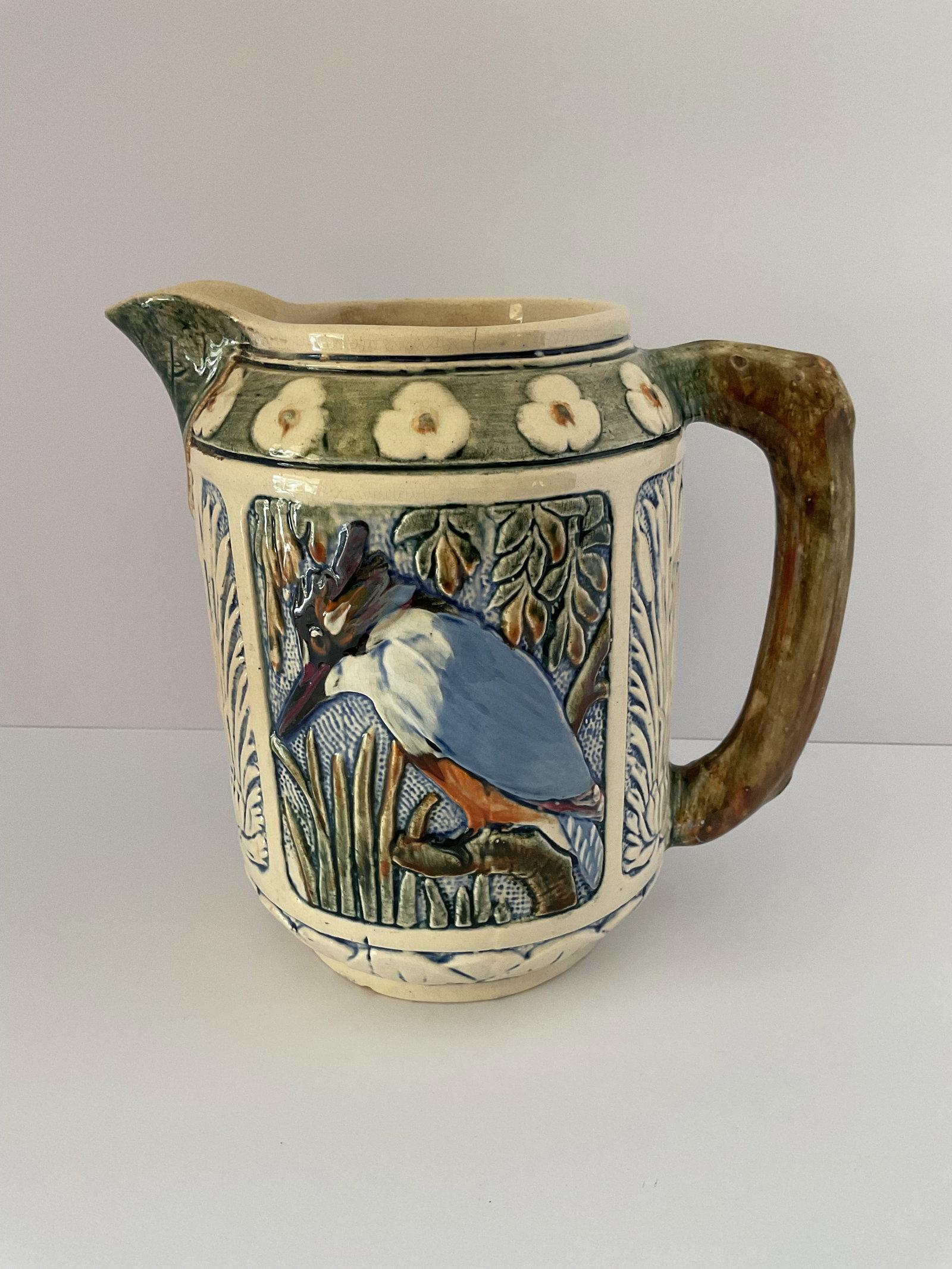 Rare Antique Weller Zona Kingfisher Pitcher: An antique Weller pitcher designed by Austrian designer Rudolph Lorber. The company introduced the Zona line in 1903 consisting of images of nature. This particular design features majolica like raise