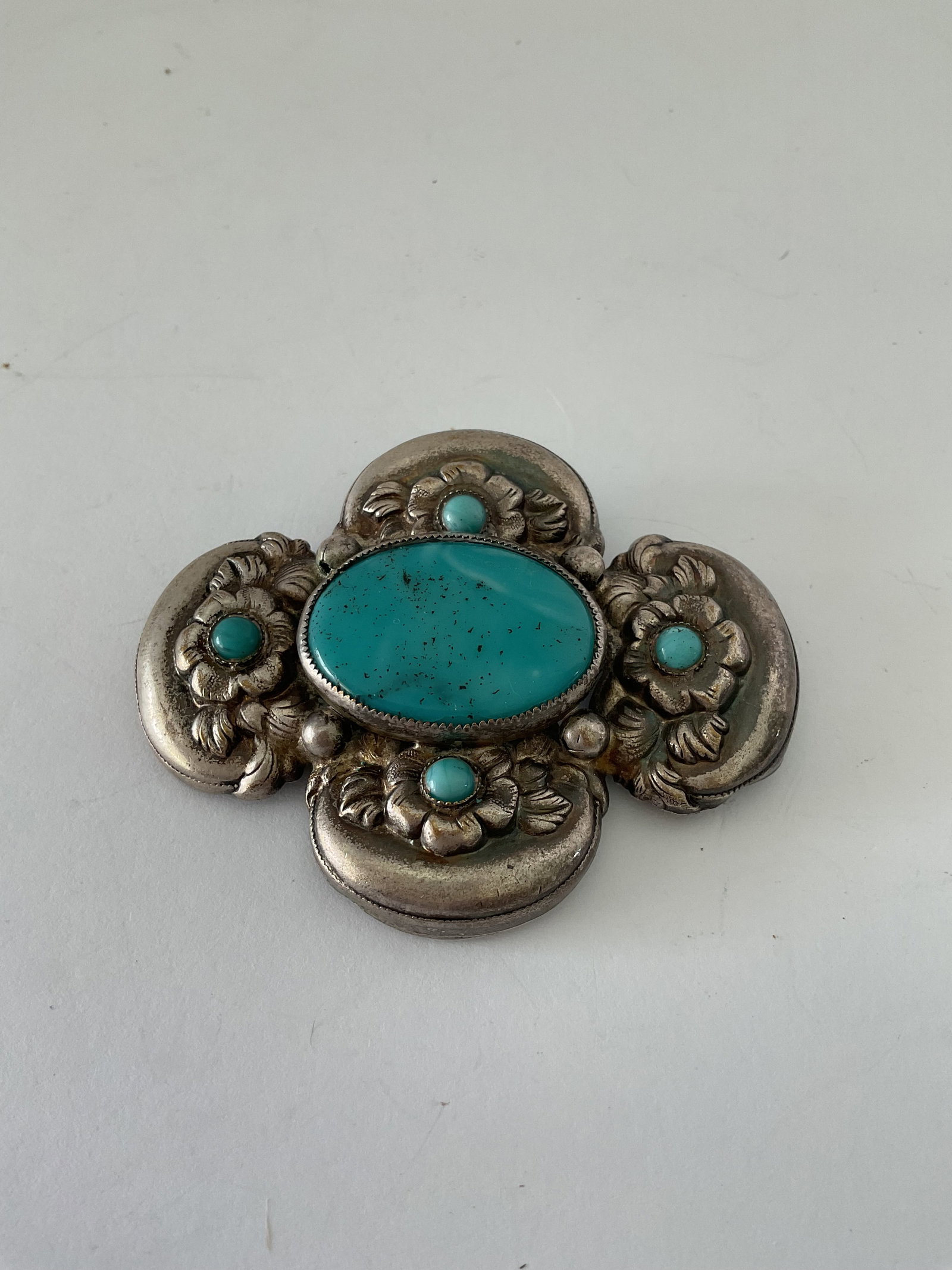 Antique Sandcast Sterling and Turquoise Navajo Brooch: An antique sterling silver and turquoise brooch. This piece has raised intricate flowers and turquoise accents. It is unmarked. It measures 3 x 2", the weight is 30.9 inclusive of stones. It has some 