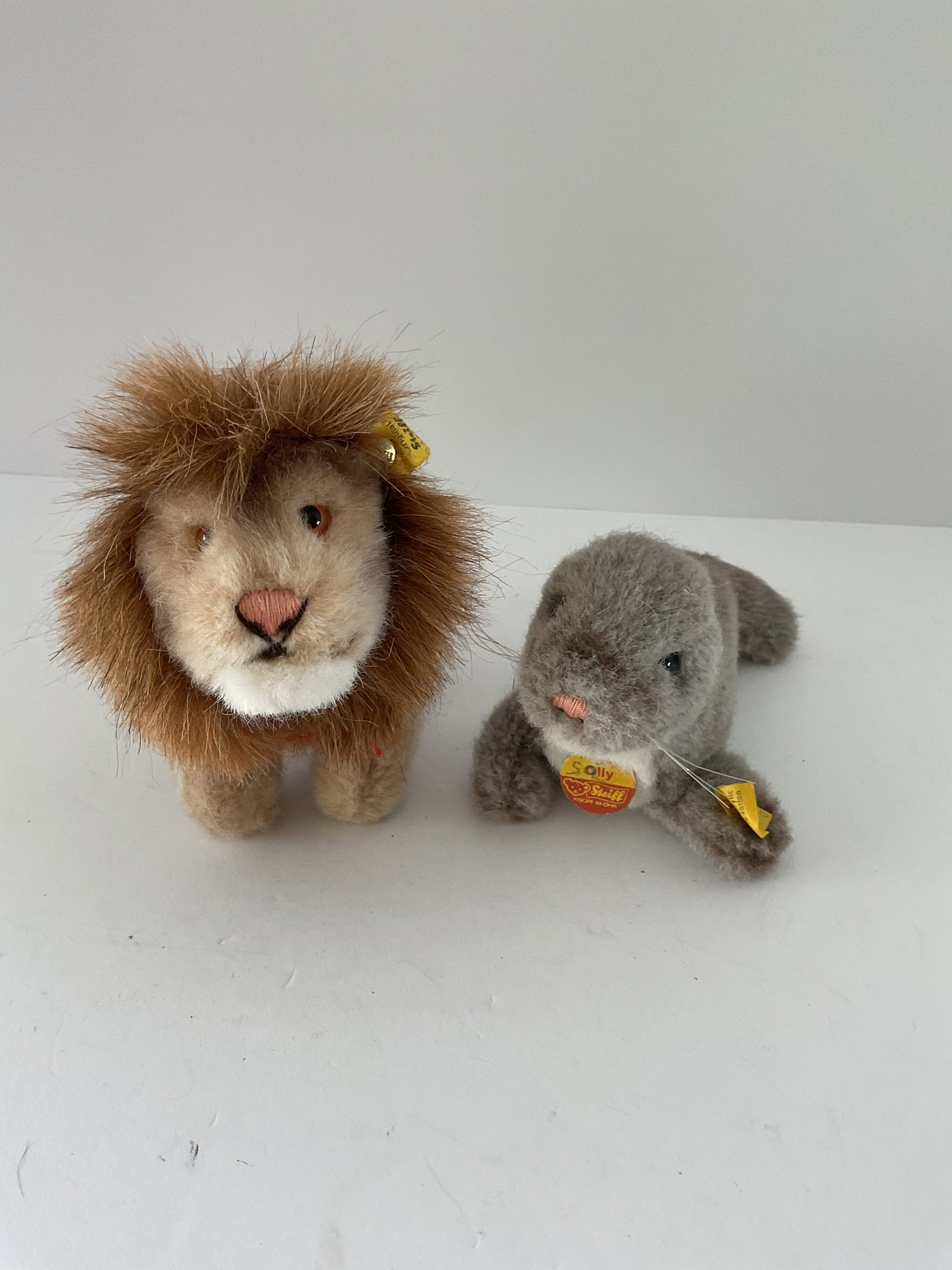 Two Vintage Steiff Animals: Included is a lion (Leo, 1460/13) and a seal (Olly 1473/09). Wool and cotton. Largest is 6 x 5” approximately. They each have tags and buttons.