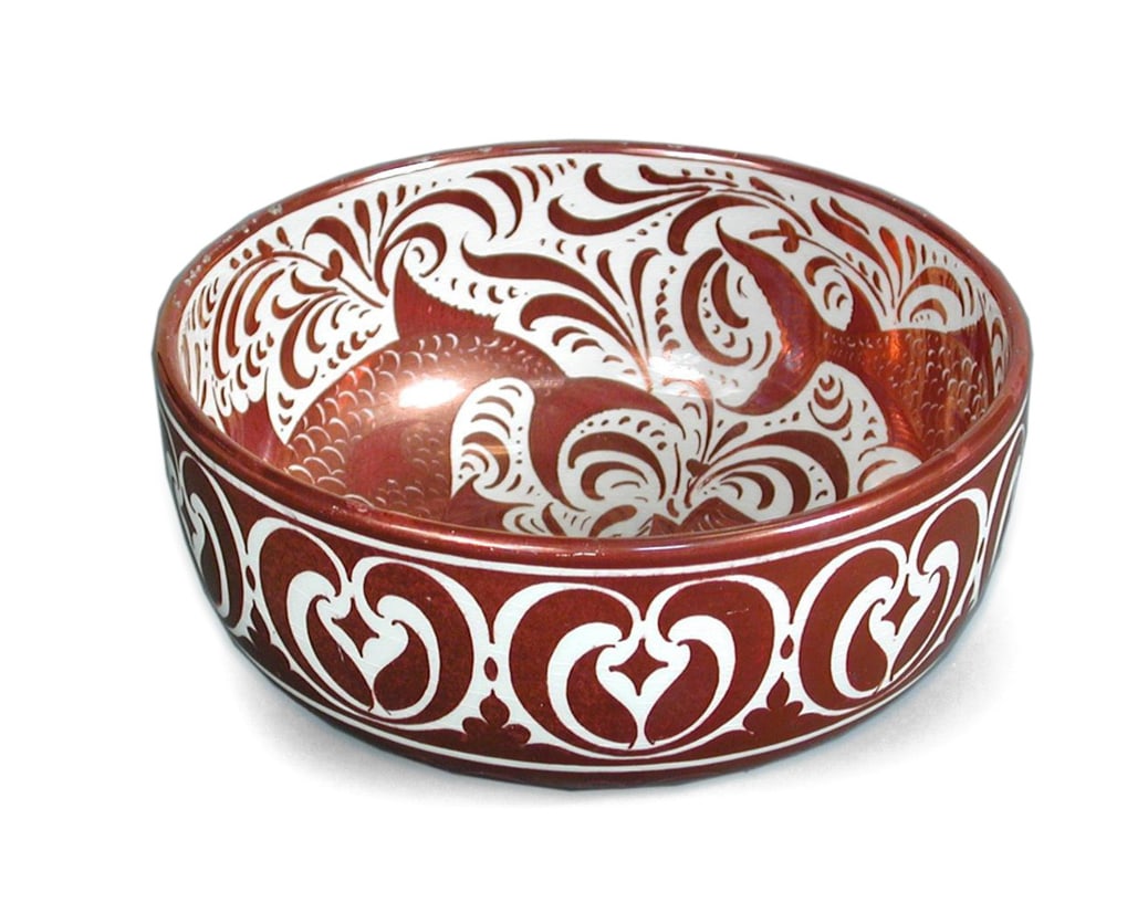 A Porcelain Bowl: Dimensions: Height 9 cm; width 19 cm. Description: A porcelain bowl decorated in iron-red and white with stylised foliate scrollwork. The rounded form is given visual energy by the bold scrolling